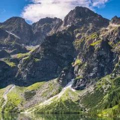 Majestatyczne, najwyższe góry w Polsce Tatry, odbijające się w spokojnej tafli jeziora.