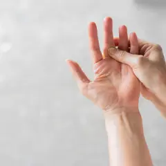 Eine Hand massiert den Bereich der Fingerknöchel, wo eine mögliche schnappfinger ursache liegen könnte.