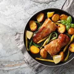 Dwie soczyste polędwiczki drobiowe w sosie, podane z pieczonymi ziemniaczkami, fasolką szparagową i cytryną.