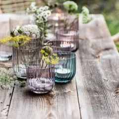 Romantische deko gartentisch mit Blumen und Kerzen in bunten Gläsern.
