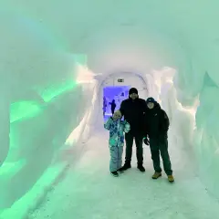 Rodzina w lodowym tunelu, gdzieś w okolicy wioski Świętego Mikołaja. Ściany lśnią zielonym światłem.
