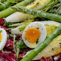 Salade colorée avec des œufs mollets, des asperges vertes croquantes et des feuilles de laitue et de radicchio.