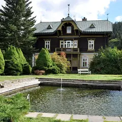 Urokliwy dworek w Karlovej Studance z basenem i fontannami, otoczony zielenią.