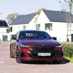 Czerwone bmw 550e na tle nowoczesnych domów.