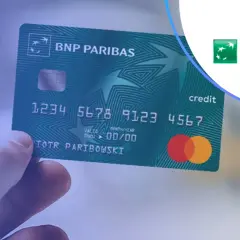 Dłoń trzyma zieloną kartę kredytową BNP Paribas. Bezpieczne BNP Paribas płatność kartą za granicą.