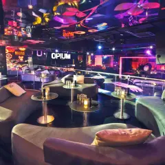 Interni lussuosi della discoteca Opium a Barcellona, con divani curvi, tavolini di vetro e luci al neon che creano un'atmosfera vibrante.