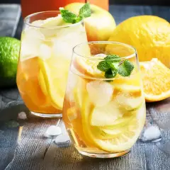 Två glas med uppfriskande vit sangria fyllda med frukt och is. Citroner, äpplen och apelsiner ger en härlig smak.