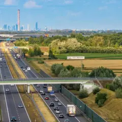 Autostrada z ruchem samochodowym i ciężarowym, w tle widać miasto. Zastanawiasz się, ile można jechać na autostradzie?