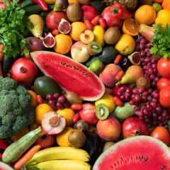 Bunte Vielfalt an Obst und Gemüse: Karotten, Brokkoli, Wassermelone, Trauben, Tomaten, Orangen, Kiwis, Pfirsiche und mehr. Eine Inspiration, wieviel Obst am Tag gesund ist.