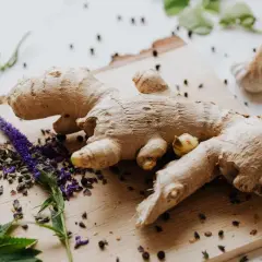 Raíz de jengibre fresca, con flores moradas y granos de pimienta. Imagina a que sabe el jengibre: picante y aromático.