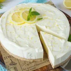 Cremige Philadelphia Torte mit Zitronenscheiben und Minze, bestreut mit Zitronenschale. Ein Stück wurde bereits entnommen.