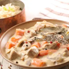 Un delicioso blanquette de ternera con zanahorias y champiñones en una cremosa salsa, servido con arroz blanco.