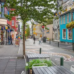 Kolorowa ulica w Reykjaviku z budynkami, flagami Islandii i artystycznymi wzorami na jezdni.