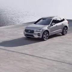 Srebrne Volvo XC60 na betonowym placu przy wodzie. Zwróć uwagę na rozmiar opon, idealnie dopasowany do SUV-a.
