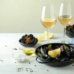 Ein festliches Essen: Muscheln mit Zitrone und Kräutern, dazu ein Glas Weißwein. Perfekt für einen genussvollen Abend.