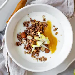 Schüssel mit Joghurt, knusprigem Granola, Nüssen, Apfelmus und Apfelstücken. Ein leckeres Frühstück!