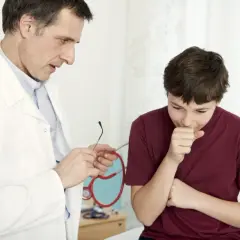 Médico examina a un niño tosiendo, buscando un remedio milagroso para la tos en niños.