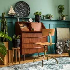 Wnętrze w stylu retro: drewniane biurko, krzesło, rośliny i dekoracje tworzą przytulną atmosferę.