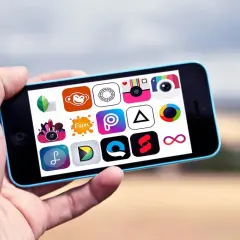 Ręka trzyma smartfon z ikonami aplikacji do obróbki zdjęć. Widać m.in. ikony aparatu, małpy i nieskończoności.