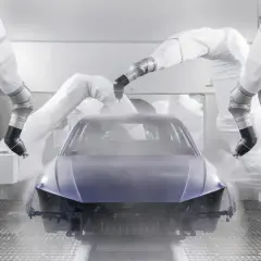 Robots pintan un coche entero en una cabina de pintura.