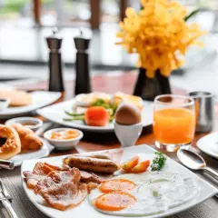 Desayuno abundante con huevos, salchichas, tocino y zumo de naranja, perfecto para tus viajes fin de semana baratos todo incluido.
