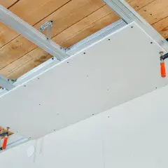 Installation d'un faux plafond en plaques de plâtre pour l'isolation phonique plafond appartement. Structure métallique fixée au plafond bois.