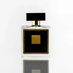 Elegancka szklana butelka perfum z czarną etykietą i złotym kwadratem.