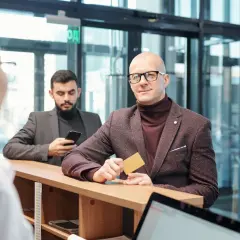 Mężczyzna z kartą w ręku, spełniający wymagania private banking, czeka przy ladzie.