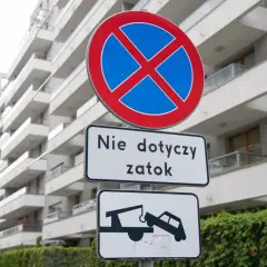 Znak zakazu zatrzymywania (B-36) z tabliczką "Nie dotyczy zatok" i piktogramem lawety odholowującej auto.