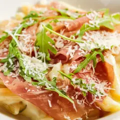Penne z kremowym sosem, szynką parmeńską, rukolą i parmezanem. Pyszne danie, które zachwyci każdego smakosza.