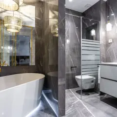 Elegante baño con bañera, ducha, inodoro y lavabo. La lámpara espejo baño ilumina el espacio con un toque de lujo.