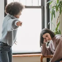 Una madre urla contro la figlia adulta, che appare abbattuta e rassegnata. Un esempio di come i genitori distruggono i figli adulti con critiche continue.