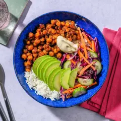 En blå skål med ris, kryddiga kikärtor, avokado, gurka, morot och rödkål. Ett perfekt bowls recept för en snabb och god middag.
