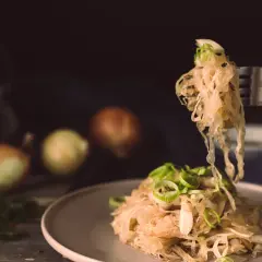 Kapusta kiszona na odchudzanie, podana na talerzu z cebulą i ziołami. Na widelcu porcja tej zdrowej przekąski.