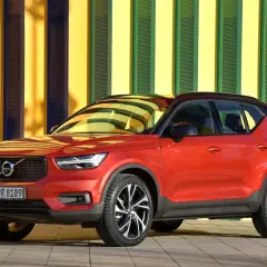 Czerwone Volvo XC40 na tle kolorowej ściany. Wiele osób szuka volvo xc40 opinie przed zakupem.