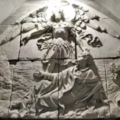 Relief mit Erzengel Michael, der einen Mann vor einem Drachen rettet. Die Szene zeigt die Namen der Erzengel in der Darstellung.