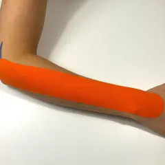 Pomarańczowy plaster kinezjotaping na przedramieniu, wspierający ćwiczenia na łokieć tenisisty.