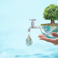 Dłoń trzyma planetę z drzewem, z której kapie kropla wody. Dowiedz się, jak oszczędzać wodę w domu.