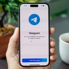 Dłoń trzyma smartfon z otwartą aplikacją Telegram. Komunikator ten jest szybki, darmowy i bezpieczny.