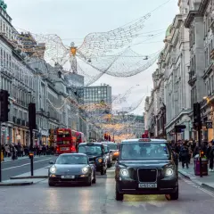Świąteczne iluminacje nad ulicą w Londynie, z charakterystycznym czarnym taksówką i czerwonym autobusem. Piccadily Circus w całej okazałości.