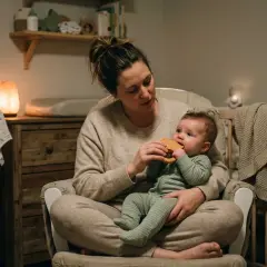 Mamma tröstar bebis med magont och ger en bitring. Mysig kvällsstämning med dämpad belysning.