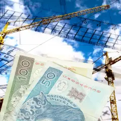 Ile kosztuje podział domu przez geodetę? Żurawie budowlane, plany i polskie banknoty symbolizują koszty inwestycji.