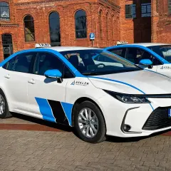 Białe taksówki z niebieskimi pasami i logo Avalon, gotowe do pracy. Idealna uber praca dla kierowców.