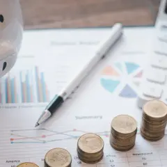 Świnka skarbonka, stosy monet, kalkulator i wykresy symbolizują finanse i rachunkowość.