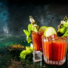Dwa drinki Krwawa Mary z łodygami selera, limonką i piklami. Idealny przepis na brunch.