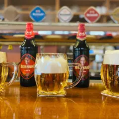 Trzy kufle z pianą i butelki piwa Bernard na barze. Idealny moment, kiedy piwo zamarza, tworząc orzeźwiający napój.