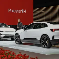 Dwa białe samochody Polestar 4 na scenie z czerwonym tłem i tulipanami.