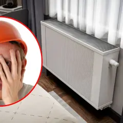 Zmartwiony mężczyzna w kasku przy grzejniku. Czyżby czekało go przelewanie wody w grzejniku?
