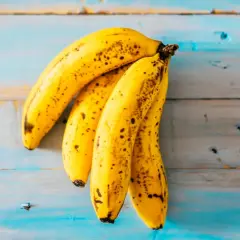 Un racimo de plátanos maduros sobre una superficie de madera azul desgastada. ¡Parece que alguien podría soñar con plátanos!