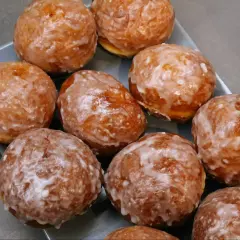 Pyszne, rumiane, pieczone paczki z lukrem, ułożone na szarej tacy. Idealne na tłusty czwartek.